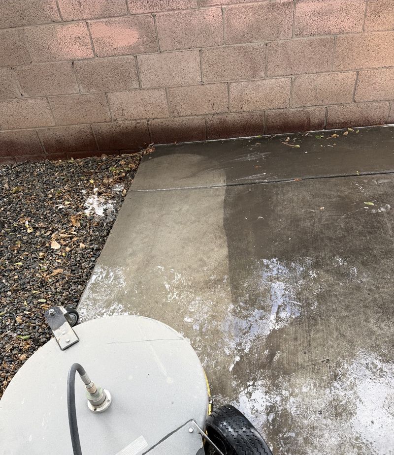 Surface cleaner attachment mid-job on a concrete pad, half cleaned