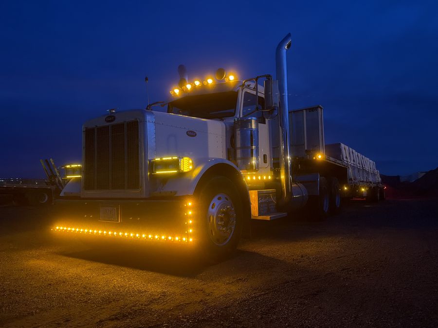 Semi truck with amber lights lit up at dusk, ready for fleet washing